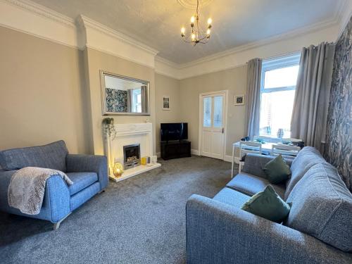 a living room with two blue couches and a fireplace at Seabreeze Apartment 1, Whitley Bay in Cullercoats