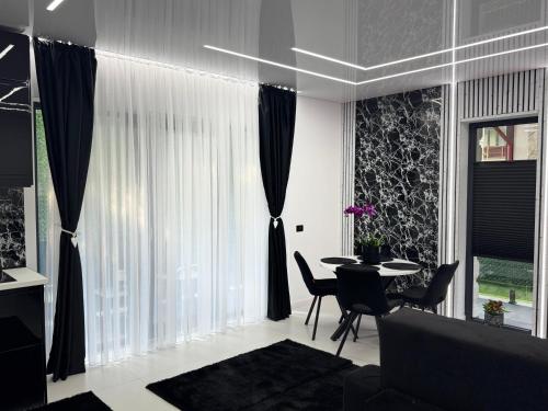 a living room with a table and chairs and curtains at HERA Elysium Apartament EROS in Sinaia