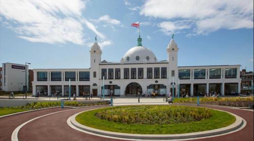 a large white building with a flag on top of it at Seabreeze Apartment 1, Whitley Bay in Cullercoats