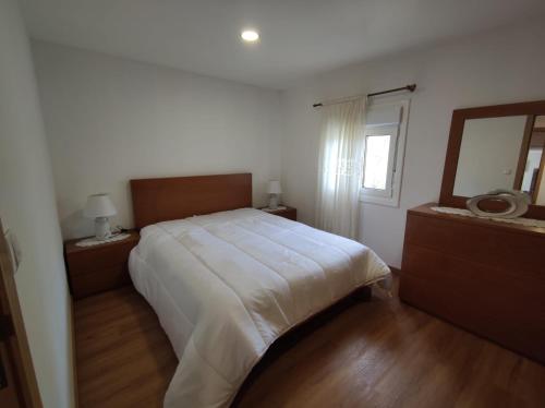 a bedroom with a large white bed and a mirror at Casinha da Eira in Monção