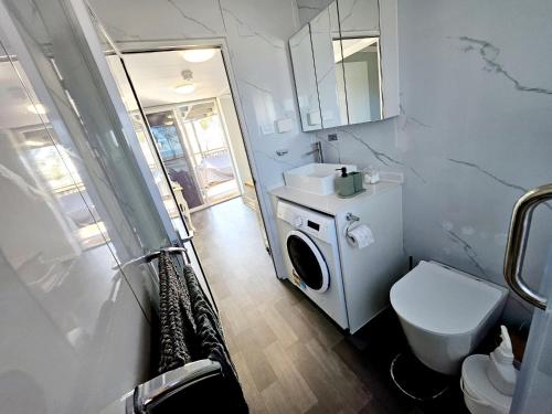 a bathroom with a washing machine and a toilet at Tiny Cottage by the Lake in Waranga