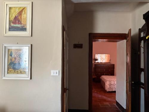 a hallway with a room with a bed and paintings on the wall at A due passi dal centro in Barga