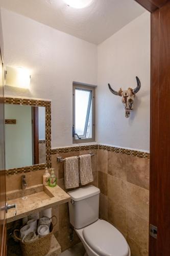 a bathroom with a toilet and a bull skull on the wall at Los Amores 09 in Bucerías