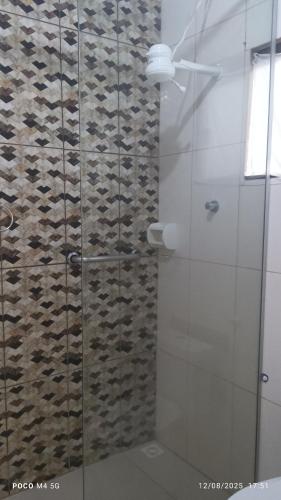 a shower with a glass door with a stone wall at Pousada santos 1, kitnet confortável com ar condicionado in Londrina