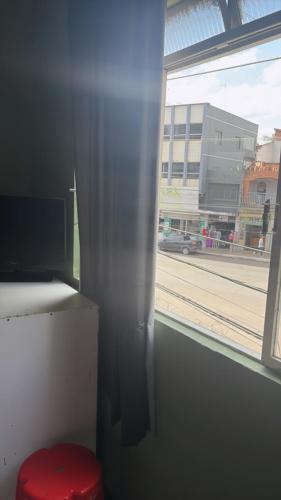 a red stool sitting next to a window with a view of a street at hotel laren in Sete Lagoas