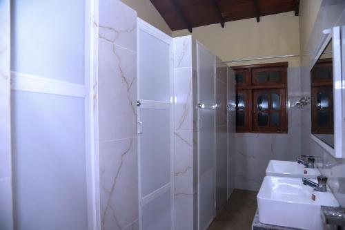 a white bathroom with a sink and a shower at Stellar Bunks in Peradeniya