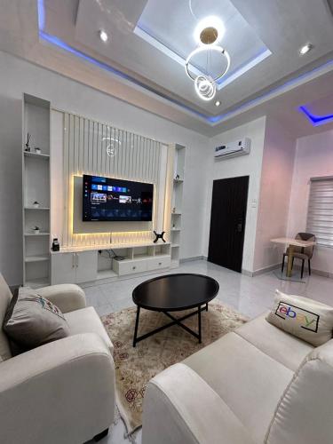 salon z kanapą, stołem i telewizorem w obiekcie SG Apartments w mieście Abudża