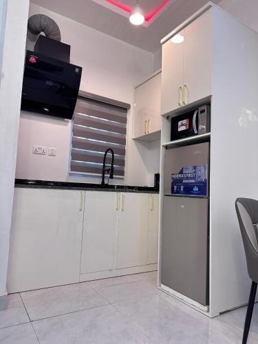 Una cocina con gabinetes blancos, un fregadero y un refrigerador. en SG Apartments, en Abuja