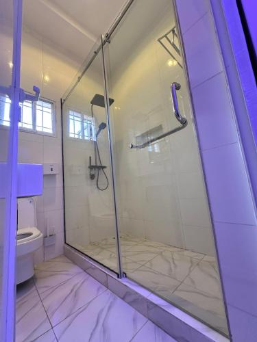 szklany prysznic w łazience z toaletą w obiekcie SG Apartments w mieście Abudża