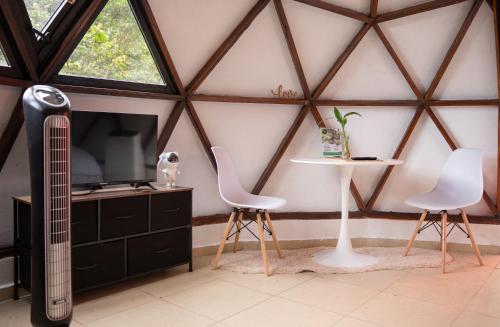 Habitación con 2 sillas, TV y mesa. en The Dome Boquete, en Bajo Boquete