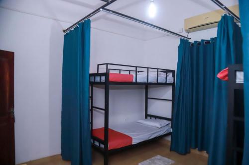 a room with two bunk beds with blue curtains at Stellar Bunks in Peradeniya