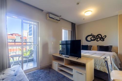 a room with a tv and a bed and a window at Higienópolis The Standard Residence in Sao Paulo