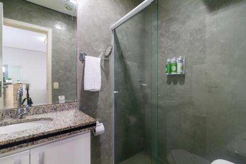 a bathroom with a shower with a sink and a mirror at Higienópolis The Standard Residence in Sao Paulo