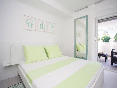a white bedroom with a large bed with green pillows at Guest house Mazuth in Rab