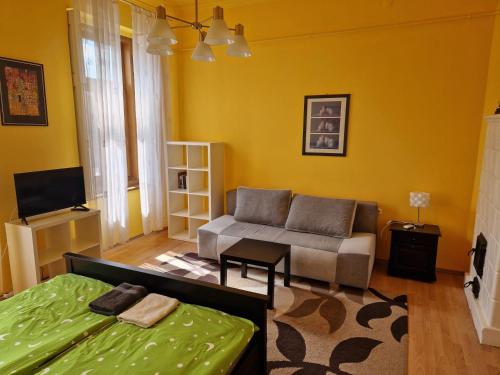 a living room with yellow walls and a couch and a bed at King Apartman in Sárvár