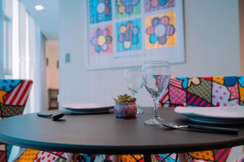 a table with a wine glass and plates on it at POX - The world of Romero Brito in the Green Tower in Santa Cruz de la Sierra
