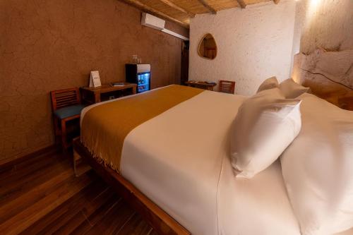 a bedroom with a large white bed with pillows at Hotel Don Raul in San Pedro de Atacama