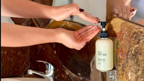 a woman is washing her hands next to a bottle of soap at Hotel Don Raul in San Pedro de Atacama