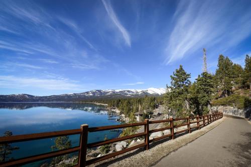 a wooden fence next to a lake with snow covered mountains at Creekside Retreat in Incline Village