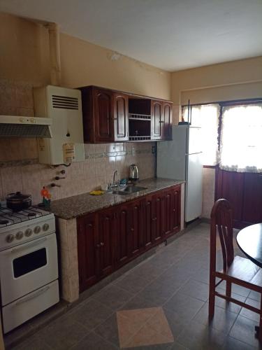 a kitchen with wooden cabinets and a white stove top oven at Alojamiento temporal - Alto Comedero in San Salvador de Jujuy