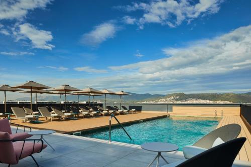 a swimming pool with chairs and umbrellas on a building at Four Points by Sheraton Barcelona Airport in Barcelona