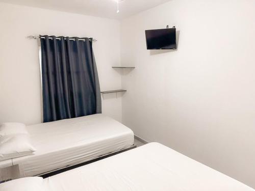 a small room with two beds and a tv at Posada Terra Santa in Tequisquiapan