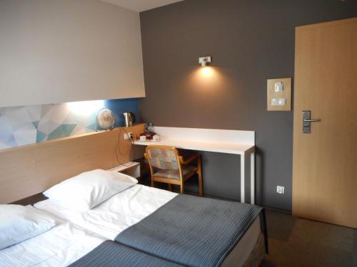 a hotel room with a bed and a desk at Hotel Platan in Ostrów Wielkopolski