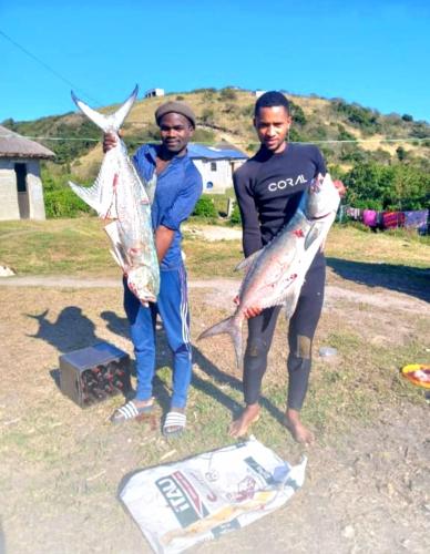 two men holding two fish in their hands at Sunrise On Sea Backpackers in Port St Johns
