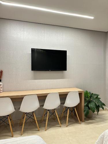 a conference room with a table and four white chairs at Flat aconchegante - Perto de Tudo - Vista Livre - Estacionamento privativo e Portaria 24h - Wi-Fi 600mbps in Brasilia