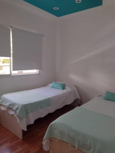 two beds in a white room with a window at Casa céntrica con piscina in Paraná