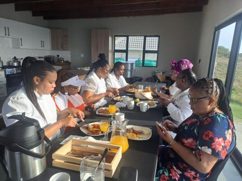a group of women sitting at a table eating food at Sunrise On Sea Backpackers in Port St Johns