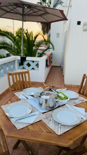 a wooden table with plates on it with an umbrella at Porto Santo Rentals in Porto Santo