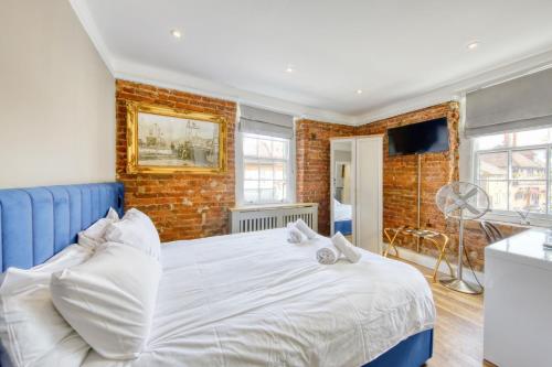 a bedroom with a white bed and a brick wall at The Foresters Arms in Kingston upon Thames
