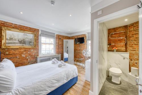 a bedroom with a bed and a brick wall at The Foresters Arms in Kingston upon Thames