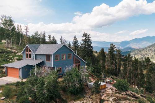 a blue house on top of a mountain at Serene Rocky MTN Retreat w Hot Tub - Pet-Friendly in Evergreen