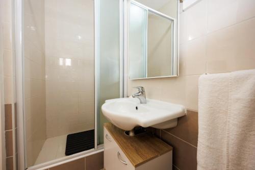 a white bathroom with a sink and a shower at Karantanovi Dvori in Murter