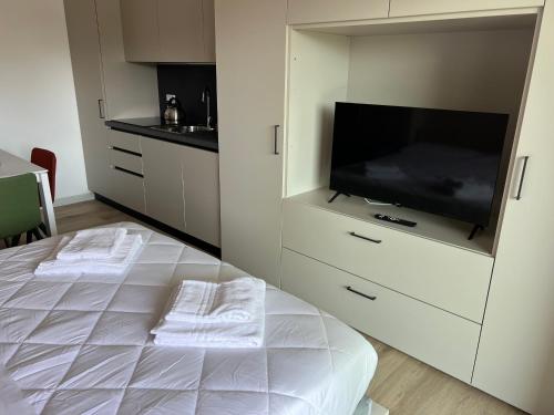 a white bedroom with a tv and a bed with towels at Montereale A6 - a Fine Experience in Pordenone