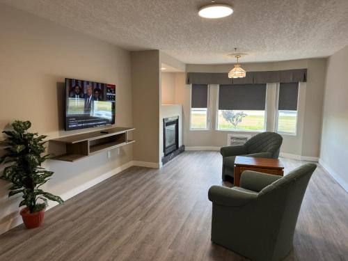 a living room with two chairs and a television at Western Budget Motel Leduc #3 in Leduc