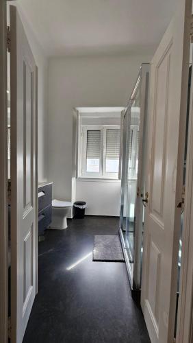 a white bathroom with a toilet and a window at SAN PEDRO Beach House in Estoril