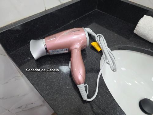 a pink hairdryer on a counter in a sink at Casa com 2 quartos na Vila A prox Paraguai e Itaip in Foz do Iguaçu