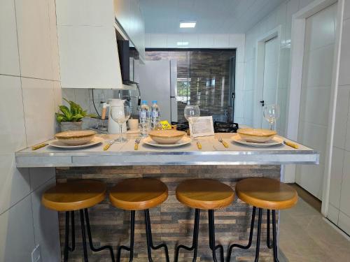 a kitchen with a counter with four bar stools at Casa com 2 quartos na Vila A prox Paraguai e Itaip in Foz do Iguaçu