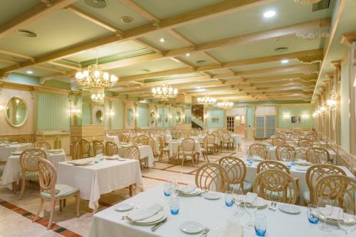 a restaurant with white tables and chairs and chandeliers at Hotel Azofra in Burgos