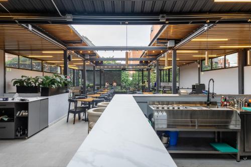 a restaurant with a long counter with tables and chairs at Qantic Lodging & Rooftop in Medellín