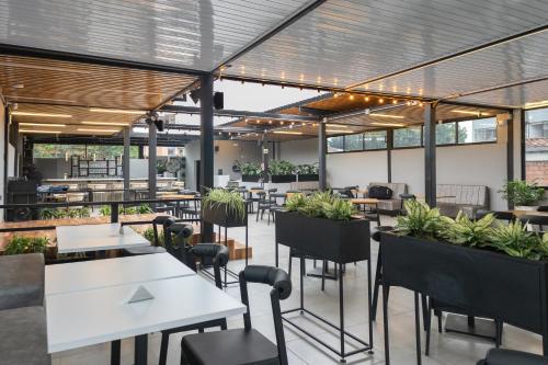 a restaurant with tables and chairs and plants at Qantic Lodging & Rooftop in Medellín