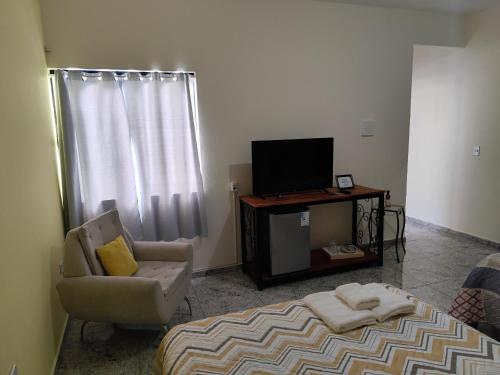 a living room with a bed and a tv and a chair at Soninho Bão - Estilo 2 in Cunha