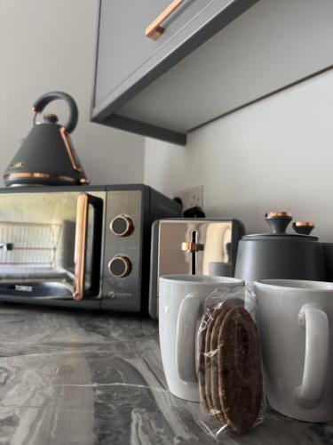 a kitchen with two coffee cups and a toaster oven at Stunning 1 BR Studio - NEC, BHX, HS2, JLR - Free Netflix in Marston Green