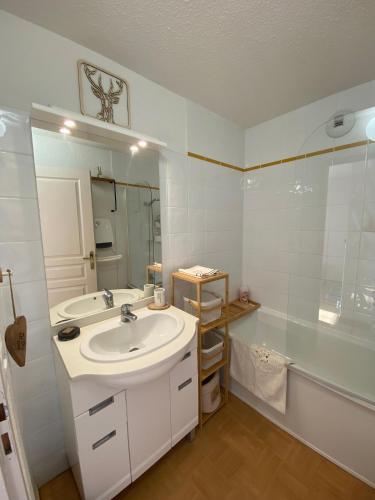 a white bathroom with a sink and a shower at L'Ecrin des Myrtilles - Appartement cosy - Piscine et vue montagne - Alpes - Val d'Arly - Aravis et Beaufortain in Flumet