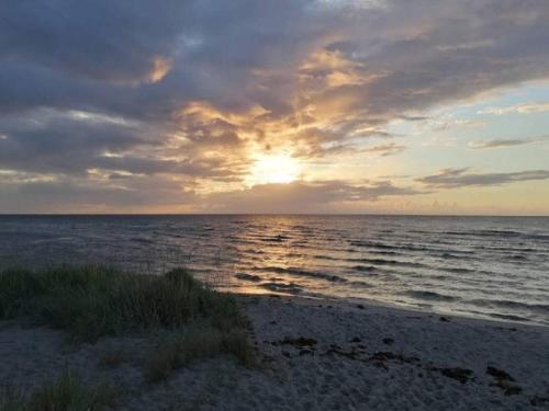 a sunset on the beach with the sun setting at 4 person holiday home in Hals-By Traum in Hals
