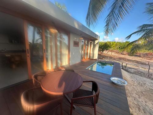 a wooden deck with a table and chairs and a pool at Refúgio do Igarapé - Atins - Bangalos in Atins