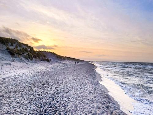two people walking on the beach at sunset at 2 person holiday home in Højer in Højer